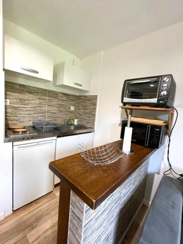 une cuisine avec un comptoir avec un micro-ondes dans l'établissement Duplex du Pailhet, T3 neuf, vue montagne, parking, navette et 2 vélos à disposition gratuitement, à Luchon