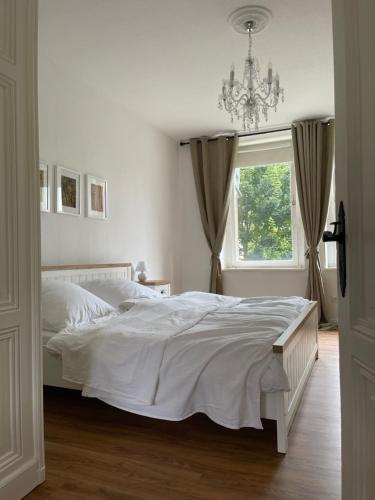 a bedroom with a white bed and a chandelier at Wohnen am Wanderbahnhof Iserlohn in Iserlohn