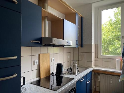 a kitchen with blue cabinets and a stove and a window at Wohnen am Wanderbahnhof Iserlohn in Iserlohn