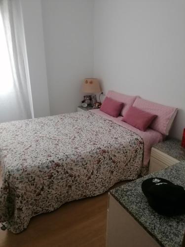 Un dormitorio con una cama con almohadas rosas. en El descanso en Mairena del Aljarafe
