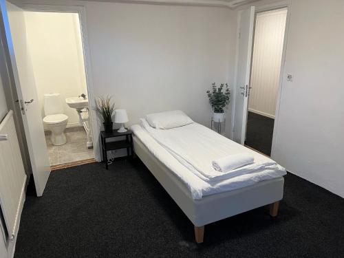 um quarto branco com uma cama e uma casa de banho em By The Bay room in a shared villa em Gotemburgo