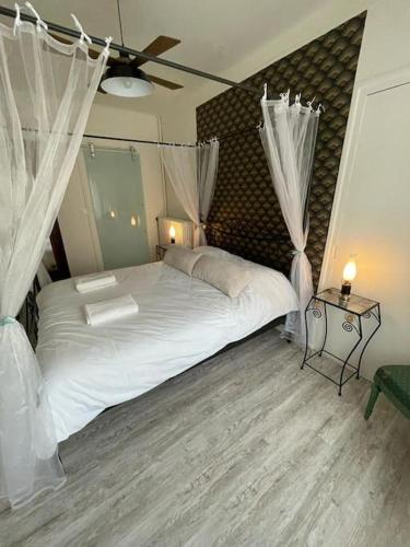 une chambre avec un grand lit blanc avec des rideaux dans l'établissement LE NID DU PHOENIX - Proche Thermes & Parcs - Rez de Chaussée, à Vichy