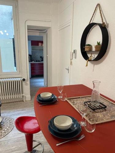 une table rouge avec des assiettes et des verres dessus dans l'établissement LE NID DU PHOENIX - Proche Thermes & Parcs - Rez de Chaussée, à Vichy