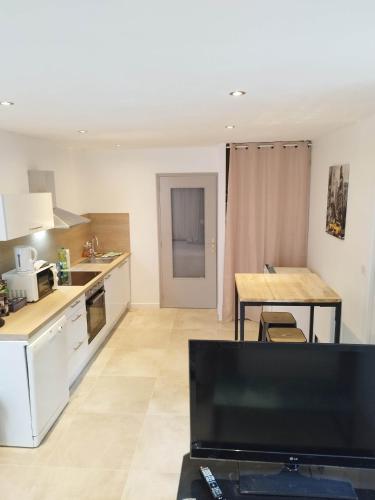 une cuisine avec des armoires blanches et une table dans une pièce dans l'établissement Le New York Bisontin 2, à Besançon