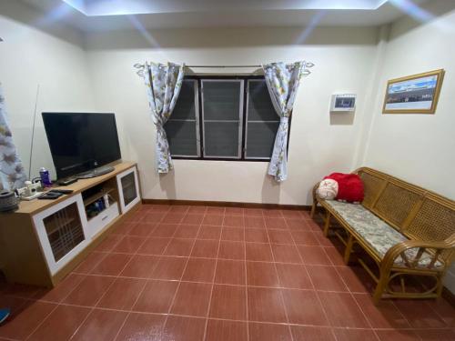 uma sala de estar com um sofá e uma televisão em สวนสน โฮมสเตย์ em Mae Hong Son