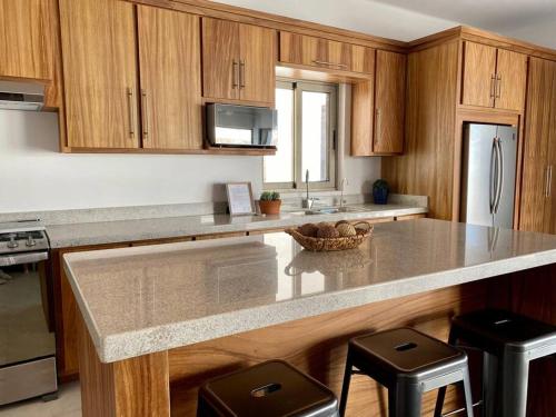a kitchen with wooden cabinets and a granite counter top at CASA SAHUARO con alberca privada, Col El Mirador in San Carlos