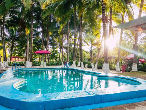 a swimming pool with palm trees in the background at Hotel y Restaurante 7 Mares in Champerico