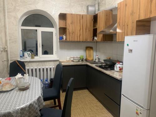 eine Küche mit einem Tisch und einem weißen Kühlschrank in der Unterkunft Laola民宿 in Almaty
