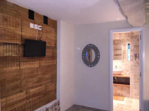 baño con TV en una pared junto a un espejo en Le Petit Paradis, en Honfleur