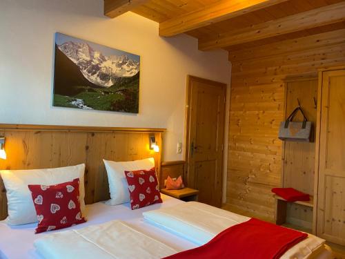 1 dormitorio con 1 cama con almohadas rojas y blancas en Alpenchalets Waldheim, en Finkenberg