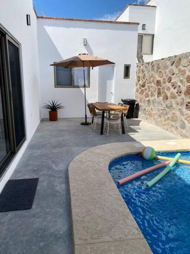 a swimming pool with a table and an umbrella at CASA PITAHAYA con alberca privada Col El Mirador in San Carlos