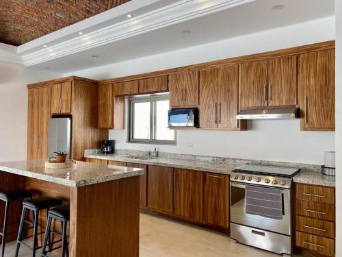 a kitchen with wooden cabinets and a stove top oven at CASA PITAHAYA con alberca privada Col El Mirador in San Carlos