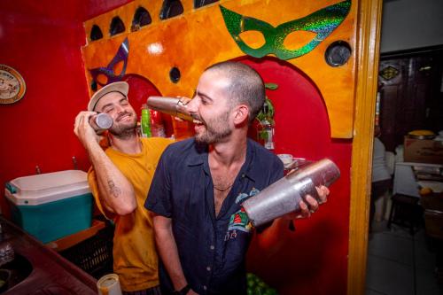 Dois homens numa sala a beber de uma garrafa. em Books Hostel no Rio de Janeiro