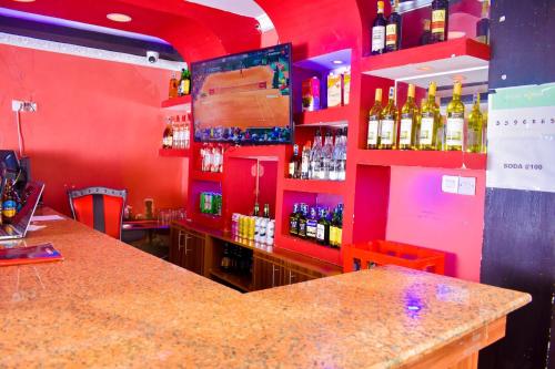 - un bar avec des murs rouges et des bouteilles d'alcool dans l'établissement Consular Resort Meru, à Meru