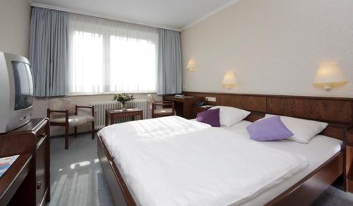 ein Hotelzimmer mit einem großen Bett mit lila Kissen in der Unterkunft Hotel Zur Windmühle in Stapelfeld