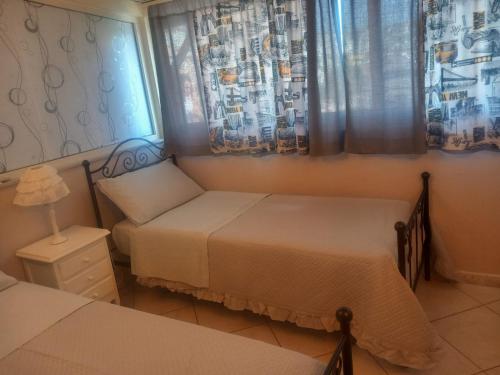1 dormitorio con 2 camas, lámpara y cortinas en Stella Marina Bed and Breakfast sul mare, en Realmonte