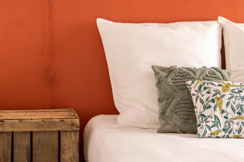 1 cama con almohadas blancas y mesa de madera en Nîmes Centre - A 5 minutes des Arènes, en Nimes