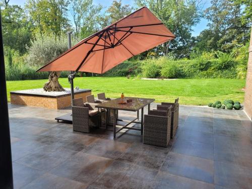 un patio con mesa, sillas y sombrilla en chambres chez l habitant villa de luxe, en Mouvaux