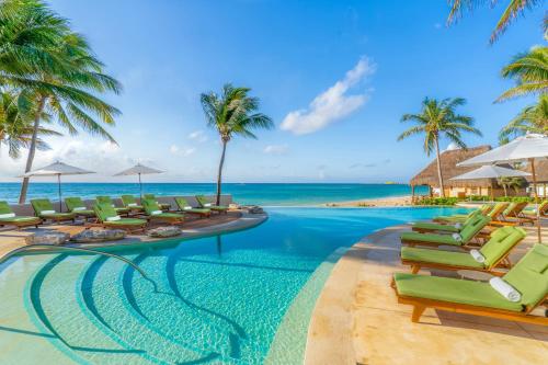 a swimming pool with lounge chairs and the ocean at Mahekal Beach Front Resort & Spa in Playa del Carmen