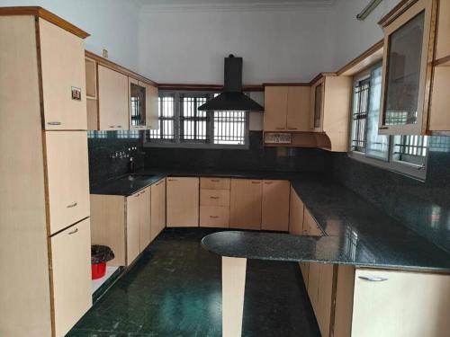 a large kitchen with a black counter top at Waterfall Villa - 4BHK in Mysore