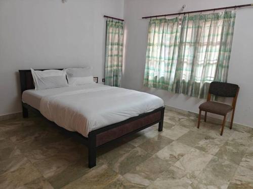 a bedroom with a large bed and a chair at Waterfall Villa - 4BHK in Mysore
