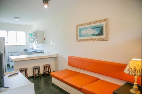 una sala de espera con sofá naranja y taburetes en Paramar en Ubatuba
