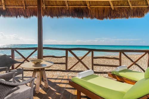 a resort patio with chairs and a table and the ocean at Mahekal Beach Front Resort & Spa in Playa del Carmen