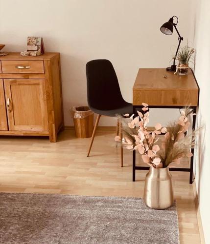 um quarto com uma secretária, uma cadeira e um vaso com flores em Freiberg homestay em Freiberg