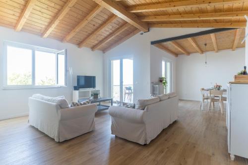 una sala de estar con muebles blancos y techos de madera. en Garda Lake Panorama Villa with Garden & BBQ, en San Zeno di Montagna
