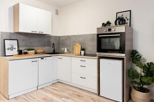 a kitchen with white cabinets and a microwave at Katowice Chorzów Park Stadion Śląski Apartmenty in Siemianowice Śląskie
