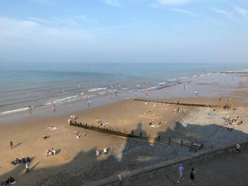 a group of people on a beach near the ocean at Cosy beach house steps from the sea in Cromer