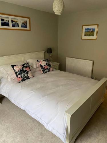 a bedroom with a large white bed with two pillows at Cosy beach house steps from the sea in Cromer