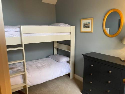 a bedroom with bunk beds and a dresser and a mirror at Cosy beach house steps from the sea in Cromer
