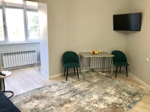 - un salon avec une table et deux chaises vertes dans l'établissement Apartment, à Taraz