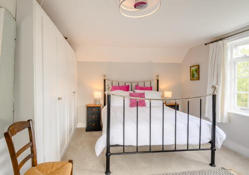 a bedroom with a bed with pink pillows at Riverside Cottage in Snape