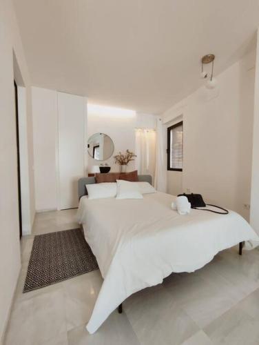 1 dormitorio blanco con 1 cama grande y espejo en Antigua Casa Hermandad en Sevilla