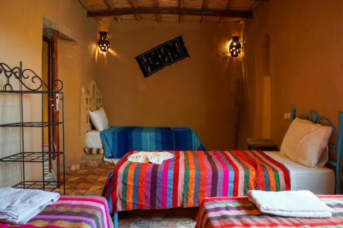 a room with two beds with colorful sheets at Riad Marhaba Merzane in Merzane