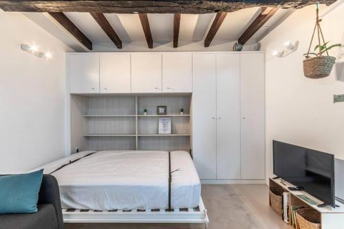 a bedroom with white cabinets and a bed and a tv at Arrantzale Etxea in Getxo