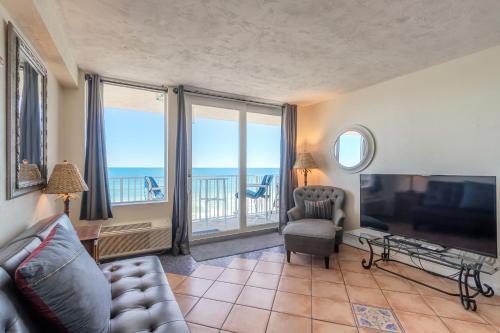 a living room with a couch and a television with a view at Direct Oceanfront Condo, Daytona Beach, sleeps 4 - with pool in Daytona Beach