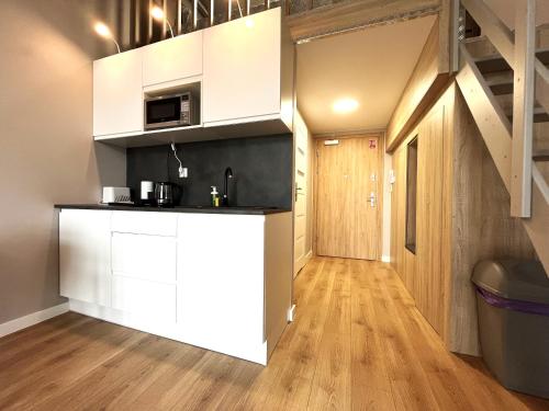 a kitchen with white cabinets and a staircase in a room at Zarembowicza 31 Apartment - Self Check-In 20h - Lift in Wrocław