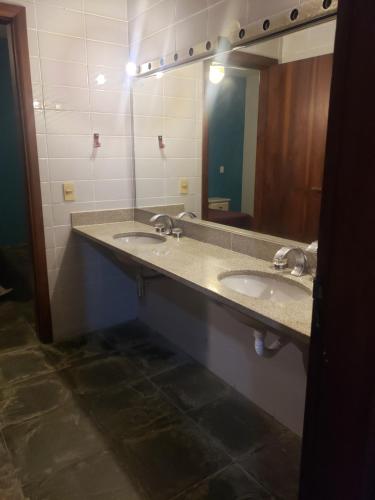 a bathroom with two sinks and a large mirror at Casa Praia Jd Acapulco in Guarujá