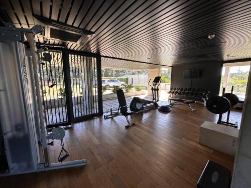 un gimnasio con cintas de correr y sillas en un suelo de madera en Apartamento frente al lago, en Montevideo