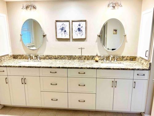 a bathroom with two sinks and two mirrors at Oasis Away Englewood, Florida! Spacious home w/ heated pool in Englewood