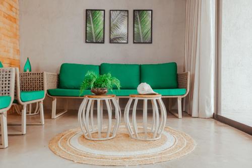 - un salon avec un canapé vert et 2 tables dans l'établissement Triplex Temporada Areia e Mar Patacho - Casa Verde, à Porto de Pedras