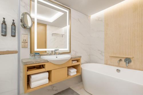 La salle de bains est pourvue d'une baignoire, d'un lavabo et d'un miroir. dans l'établissement The Westin Shenyang, à Shenyang