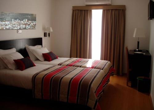 a hotel room with a bed with a striped blanket at Hotel A Esteva in Castro Verde