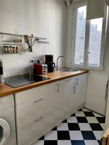 - une cuisine avec des placards blancs et un sol en damier dans l'établissement Beau studio spacieux, à Paris