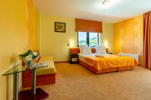 a hotel room with two beds and a glass table at Saint George Mountain Residence in Belashtitsa