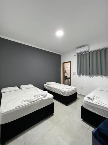 um quarto com duas camas e uma janela em Colliseu Hotel Pousada em Aparecida