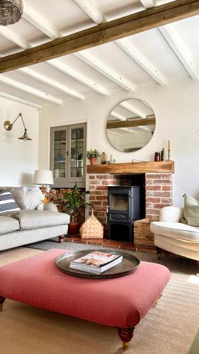 Grundisburgh的住宿－Charming 3 bedroom house in Woodbridge area，客厅设有壁炉和红色地毯。